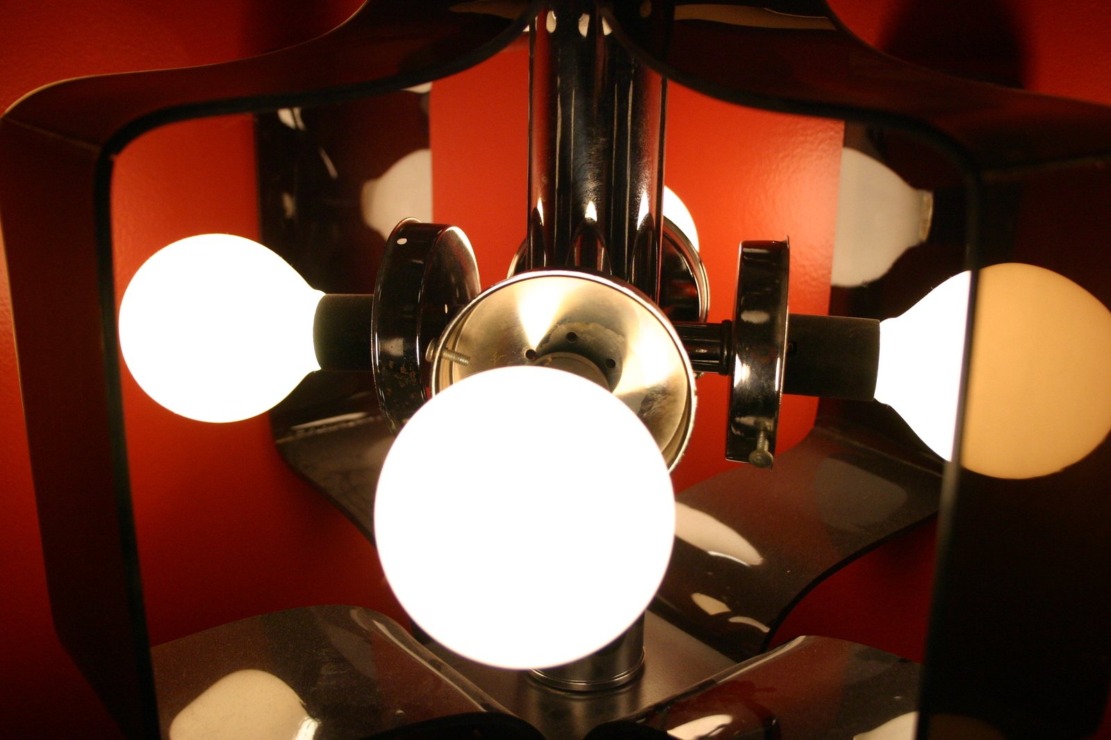 a chandelier with multiple lit bulbs and circular mirrors