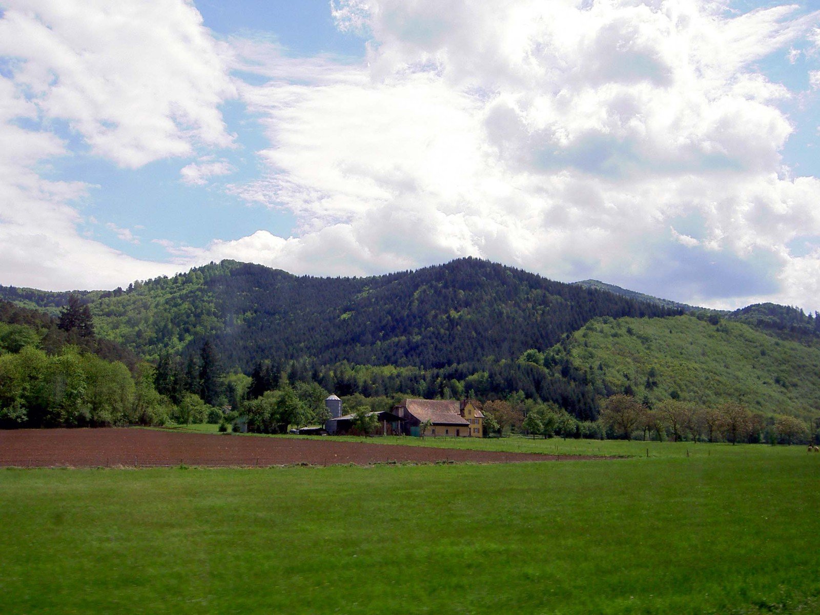a farm is in the foreground and a distant hill in the distance