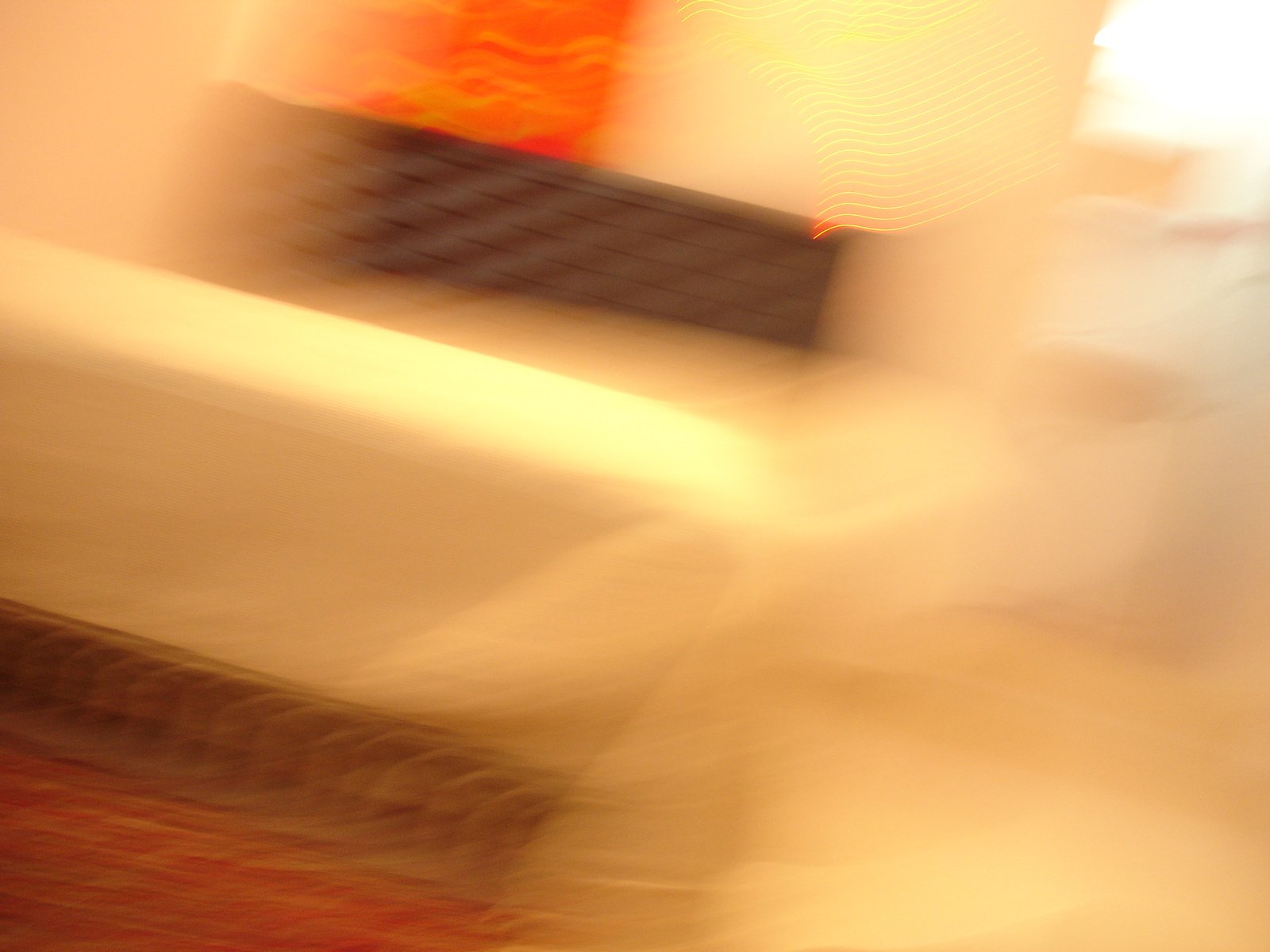 a blurry image of an orange vase next to a chair