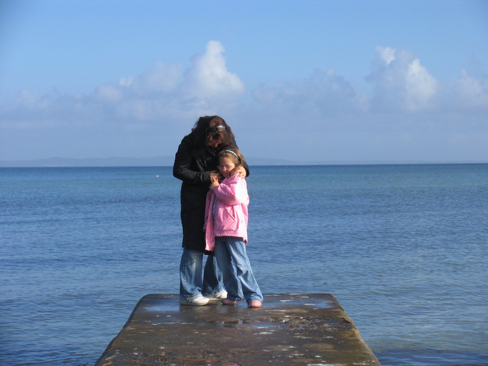 a man holding a child on the end of a dock