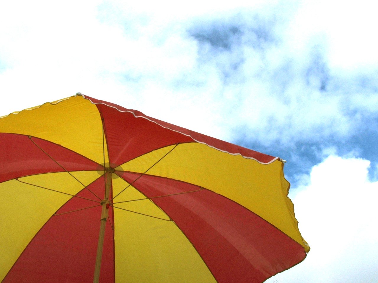 an umbrella that is yellow and red with clouds in the background