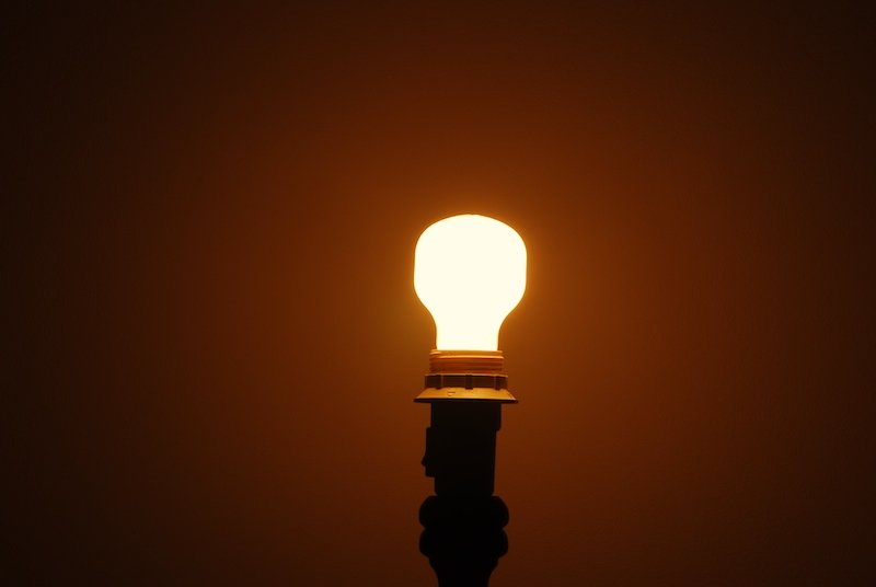 a single light bulb on top of a black pole