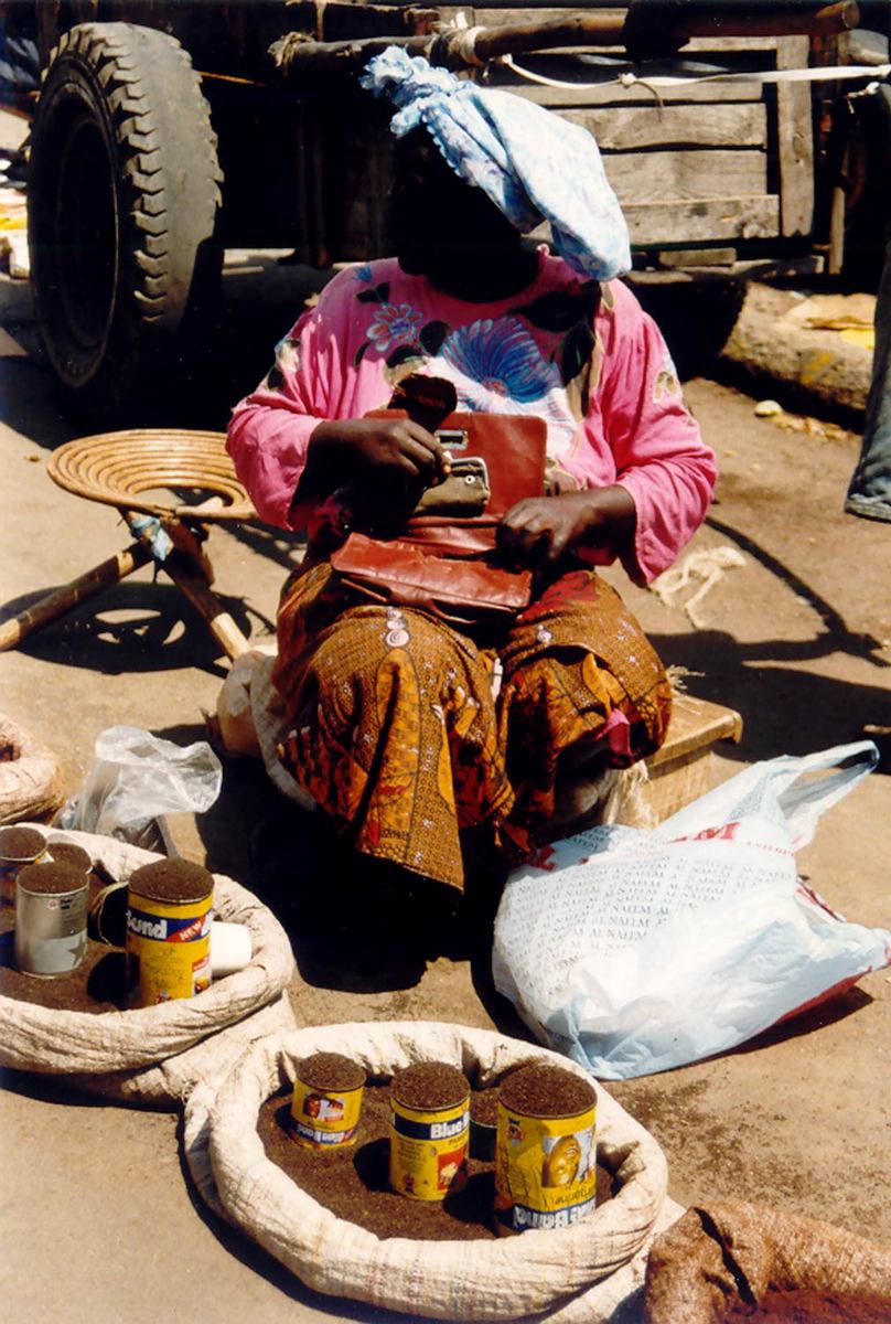 a woman sitting on the ground in front of bags and pots