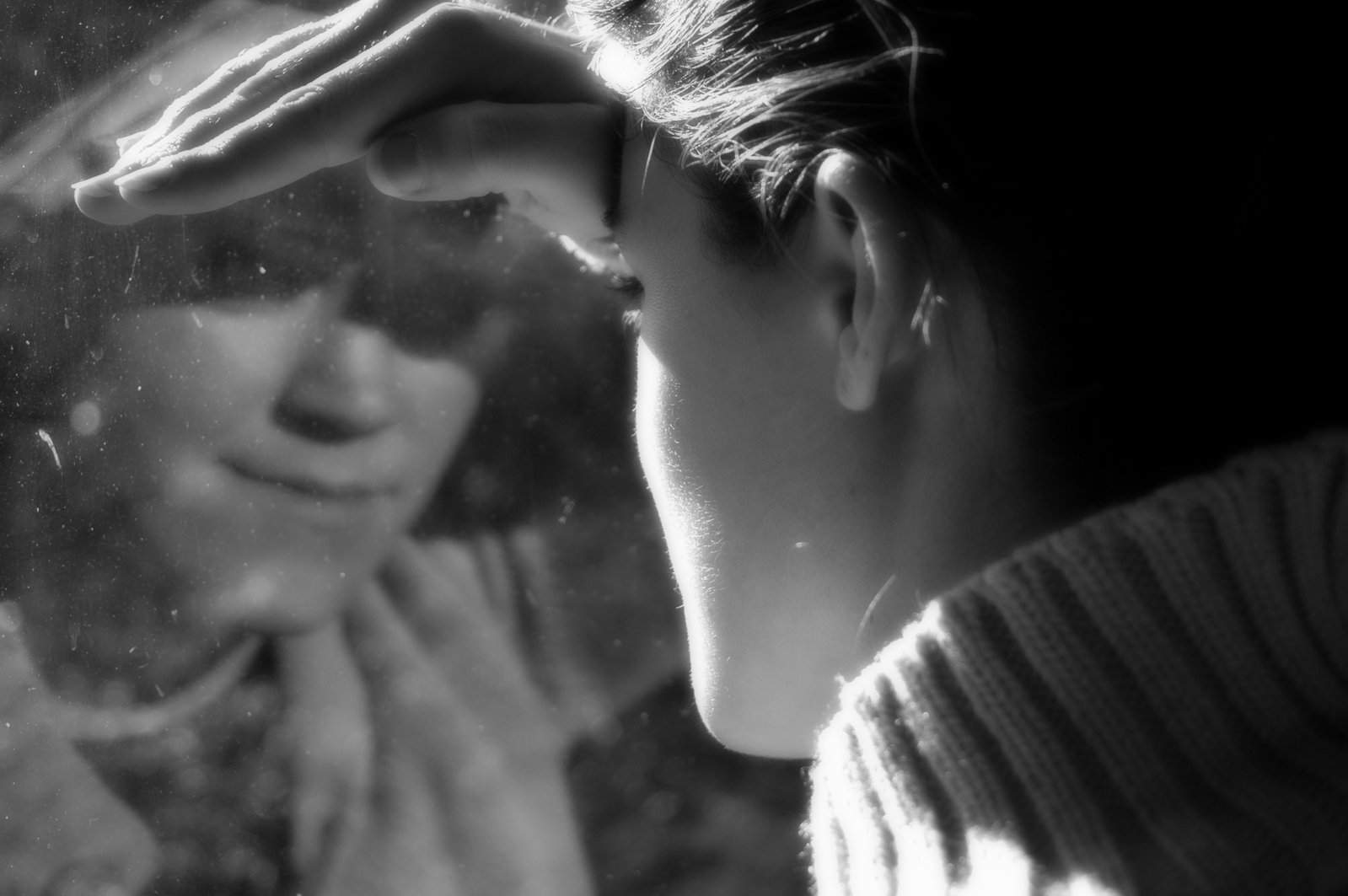 a woman staring in the mirror touching her head