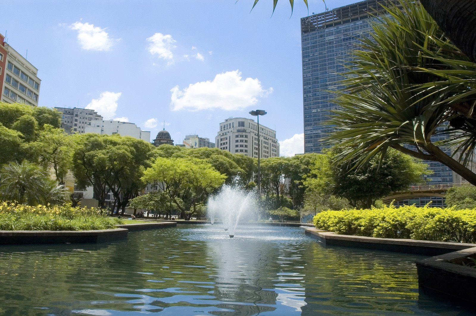 a fountain surrounded by lots of trees in front of buildings