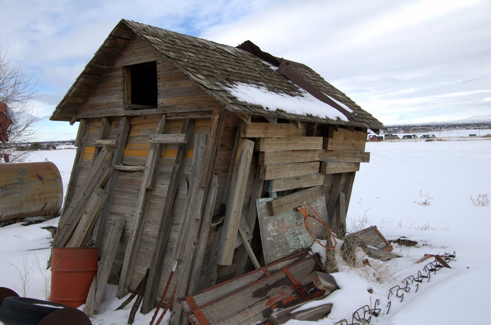 a large wooden shack with broken windows on a snowy day