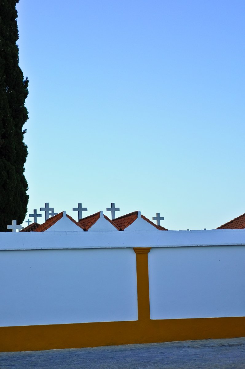 white fences topped with crosses against a blue sky