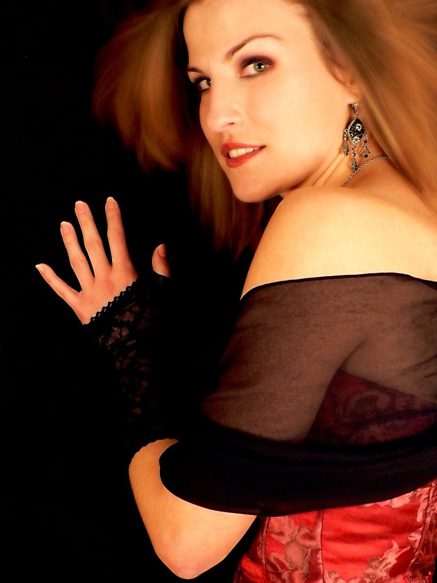 a woman with brown hair is wearing black gloves and a red dress