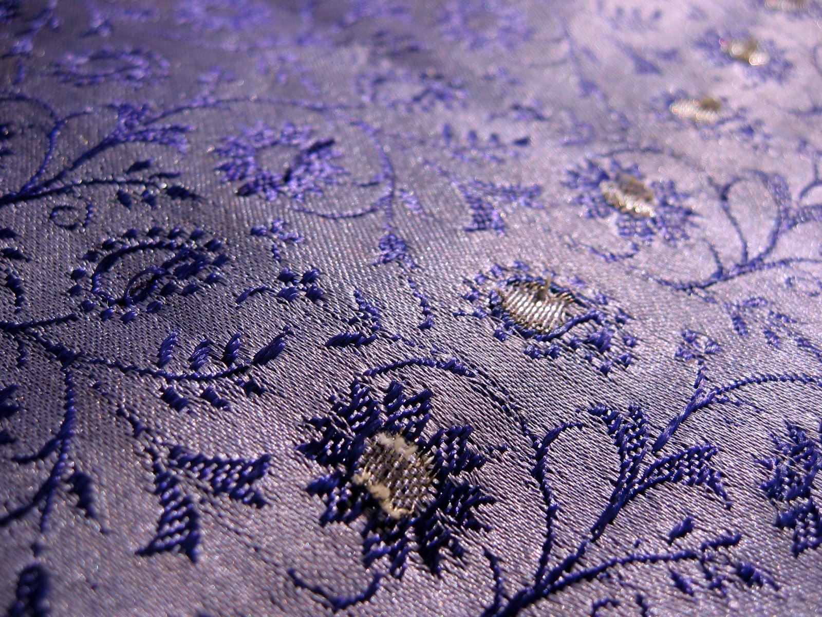a blue and gold textured fabric with floral vines