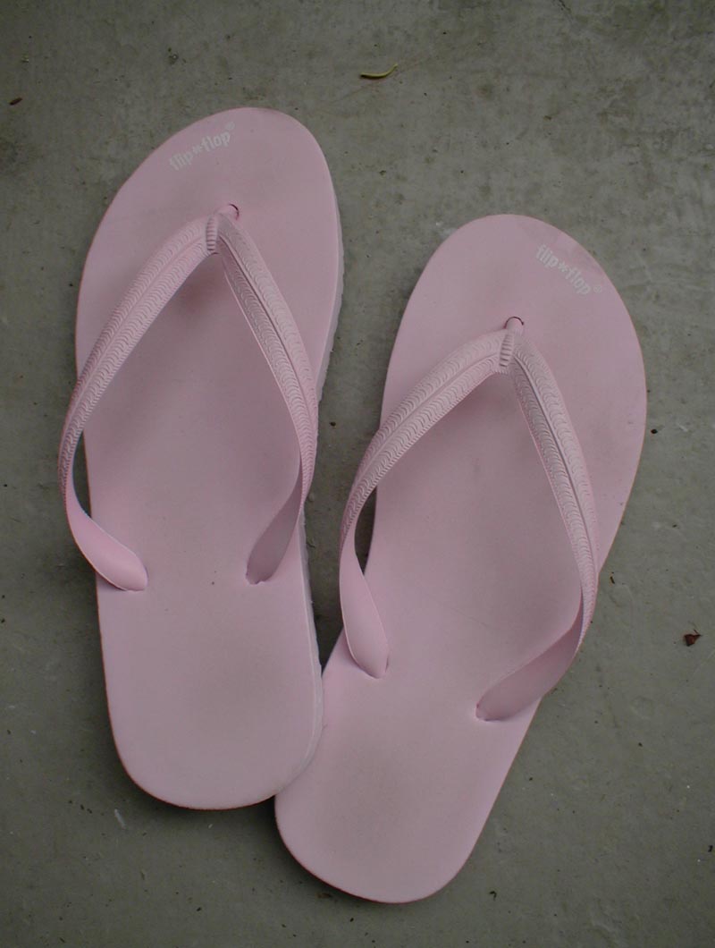 two pink flip flops laying on the ground
