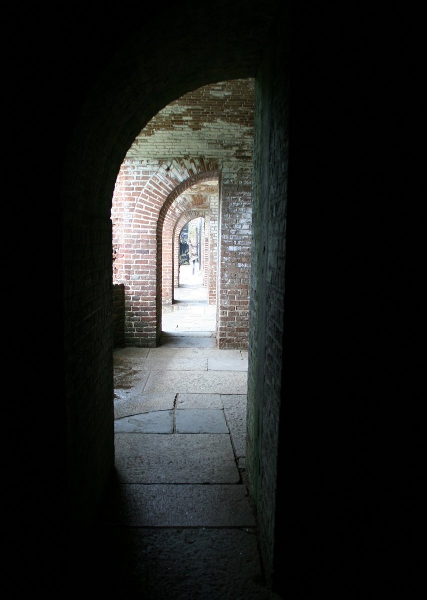 a hallway with arches and bricks in the dark