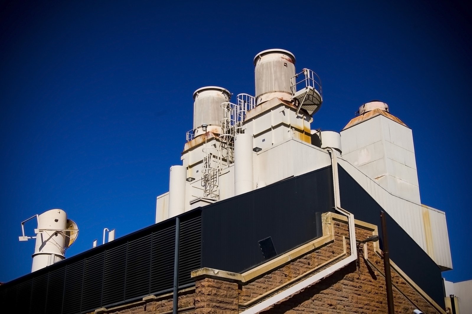 the outside of an old factory with multiple chimneys and large windows