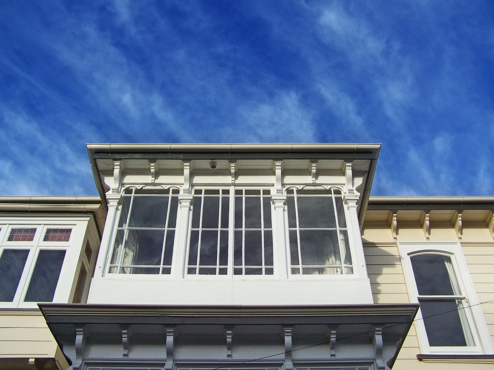 an old house has white windows and blue sky