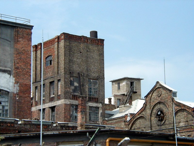 some tall brick buildings with a clock and flag flying in the air