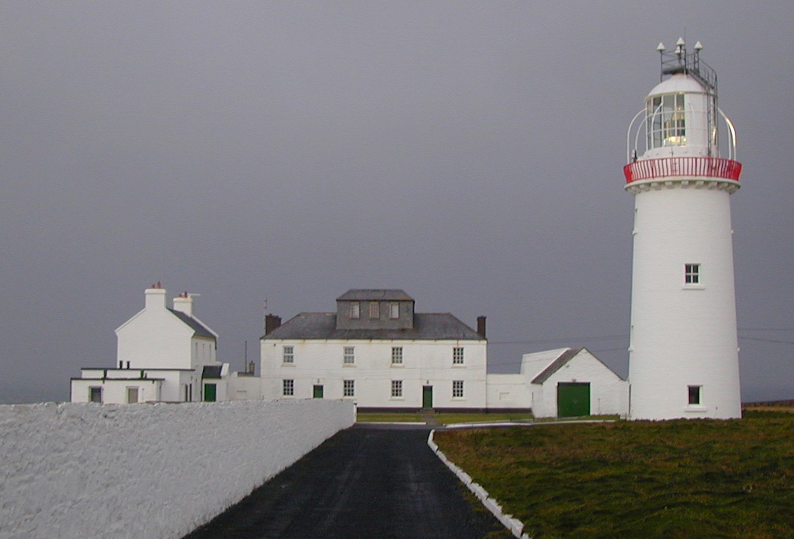 a lighthouse is lit up in the cloudy sky