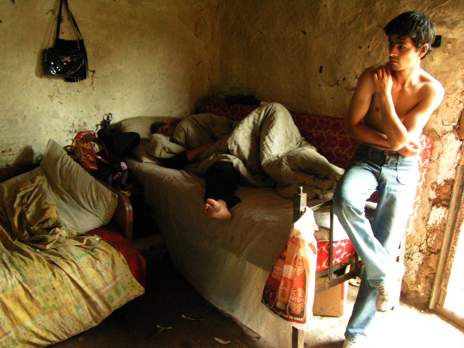 a man is sitting on a chair in front of a small bed