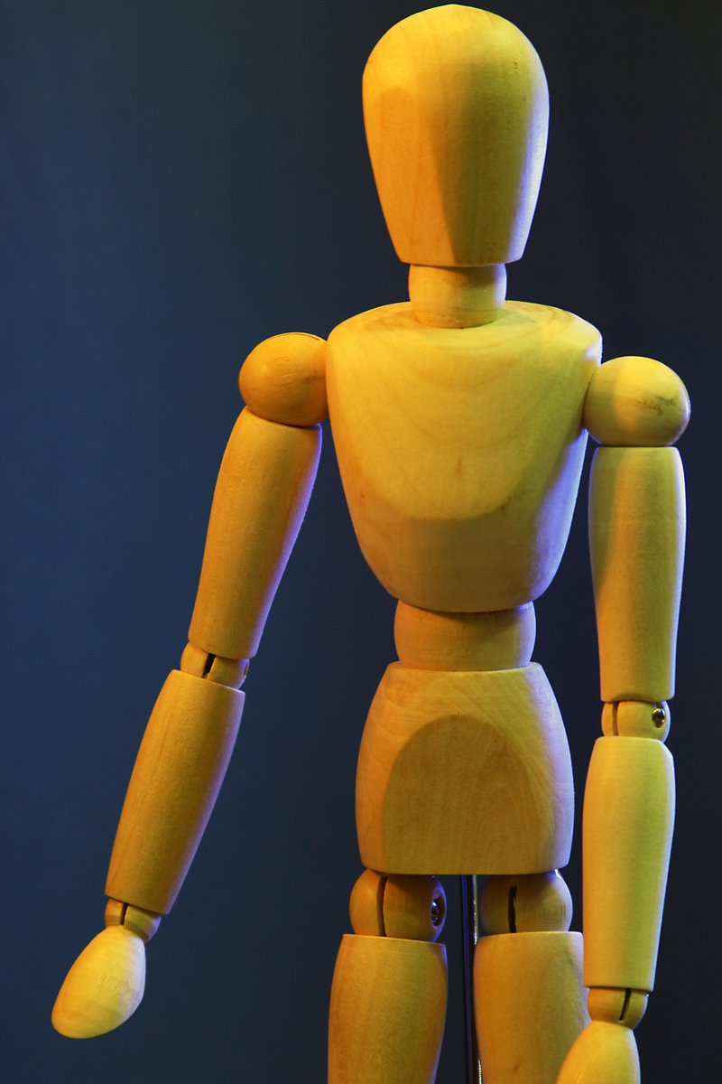 a yellow wooden robot model standing still