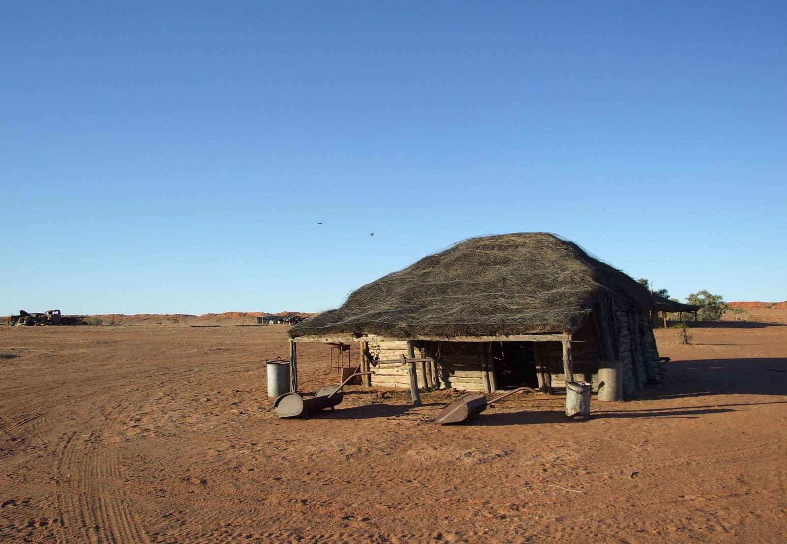 an old, thatched building with a few wheels in a desert area