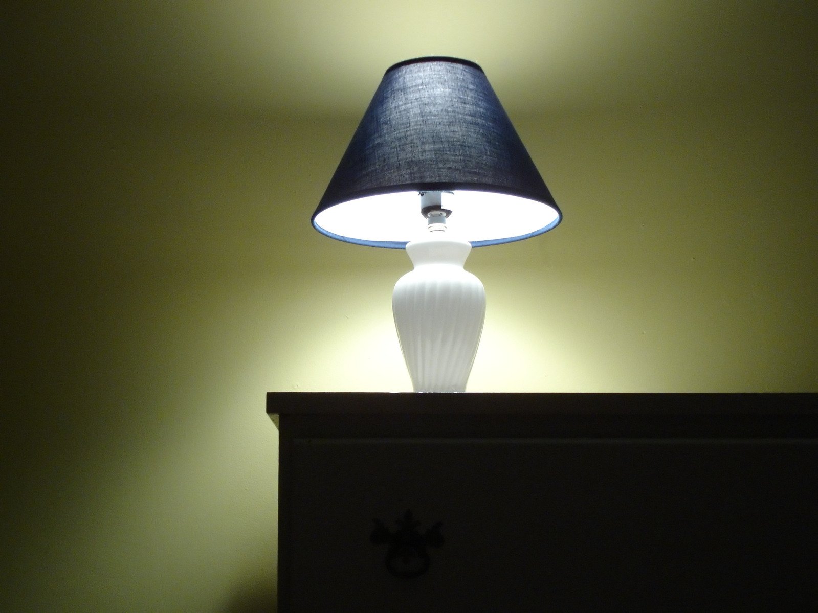 a light that is on and next to a dresser