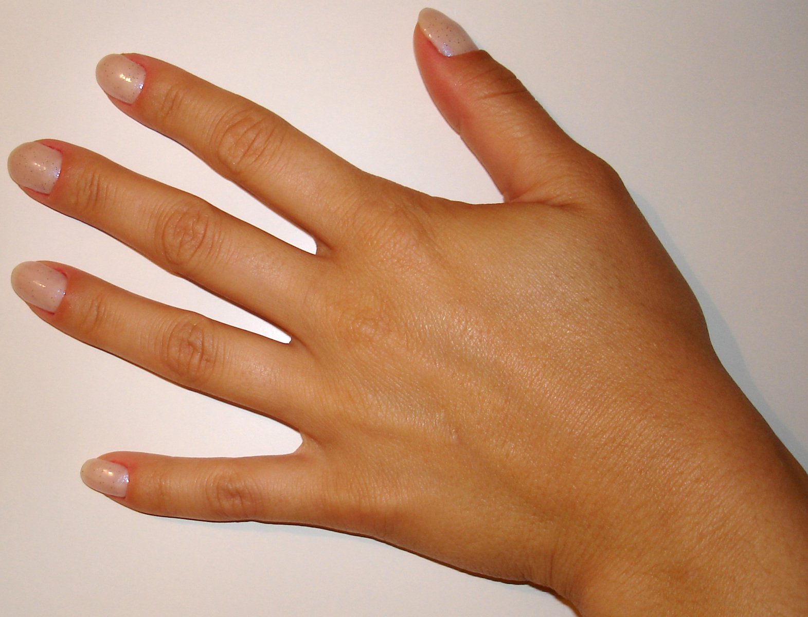 a person's hand with some pink nails and a pink cat on the corner of the picture