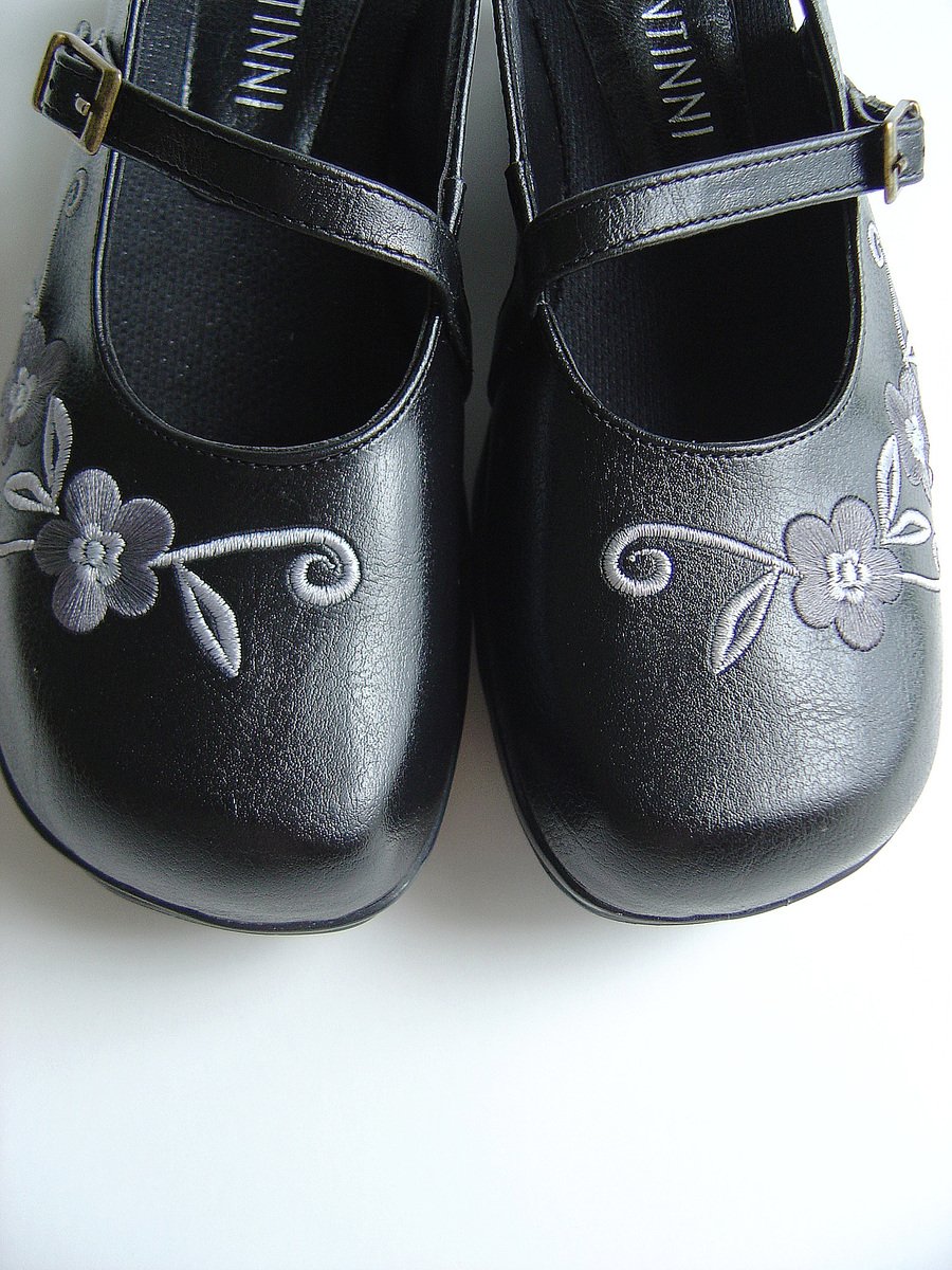 pair of shoes with black leather flowers and ribbons
