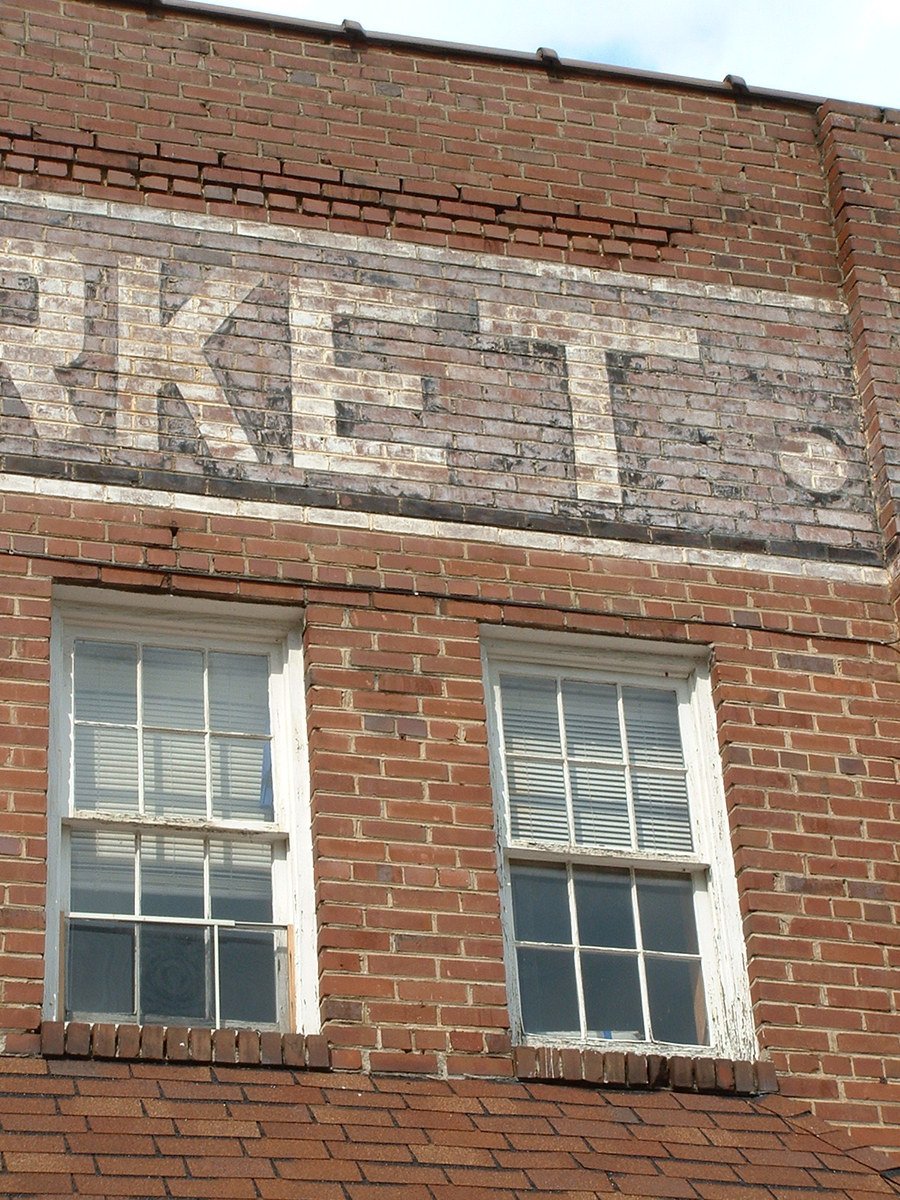 an old brick building with white windows and a faded sign on the side