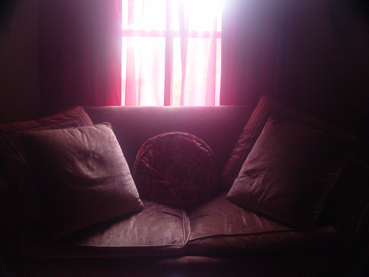 a couch sitting underneath a window covered in curtains