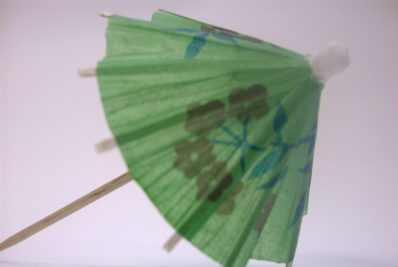 a green fan is held on a wooden stick