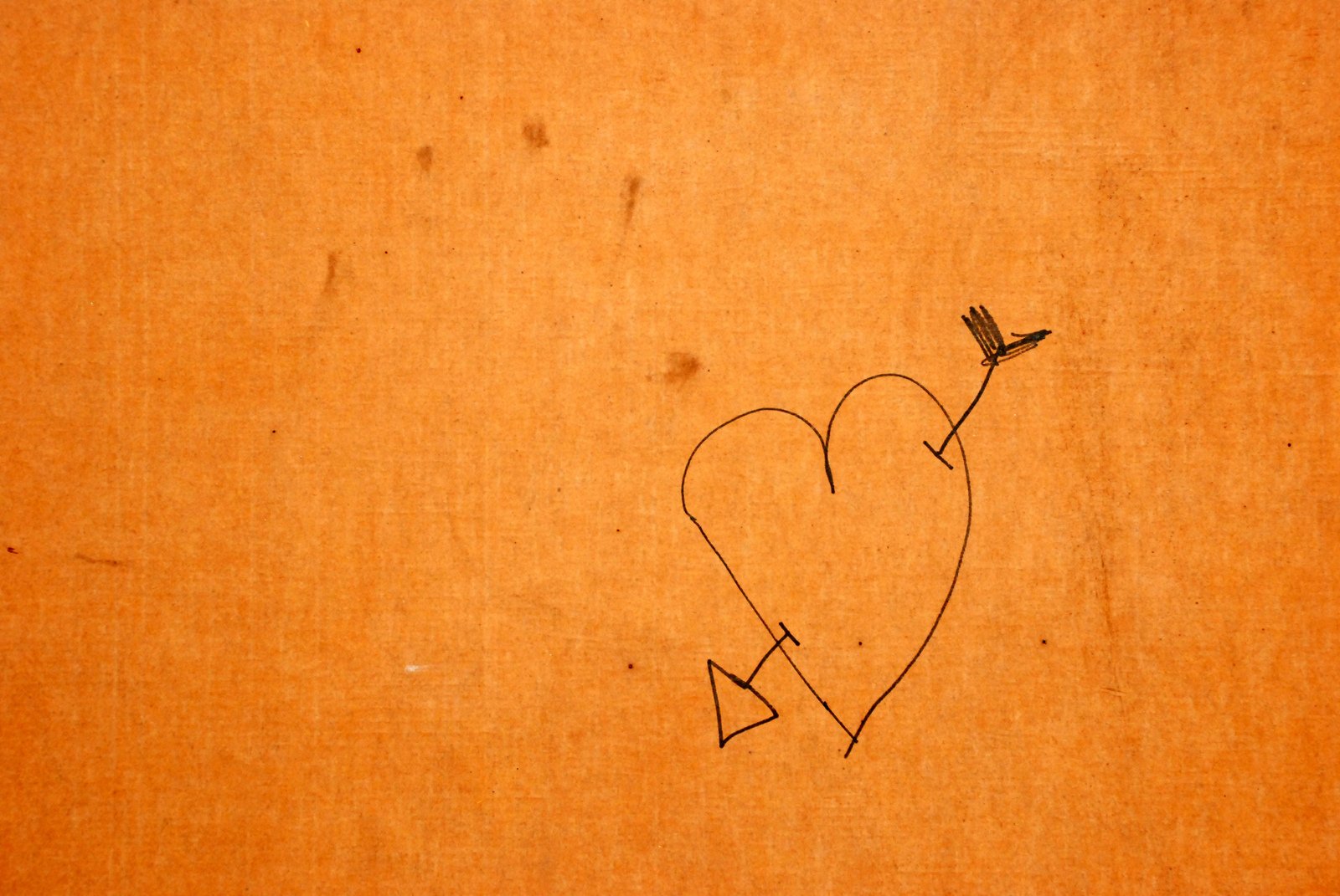 a hand drawn heart and arrow on a brown card