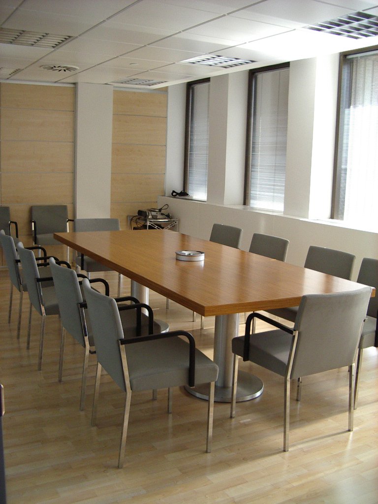 an office conference room with a big table and grey chairs
