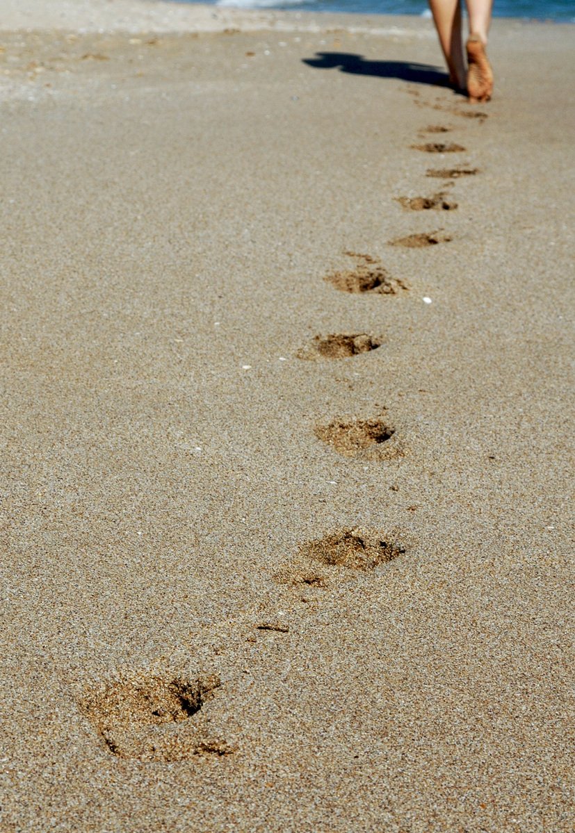 a person walks on the beach toward the ocean