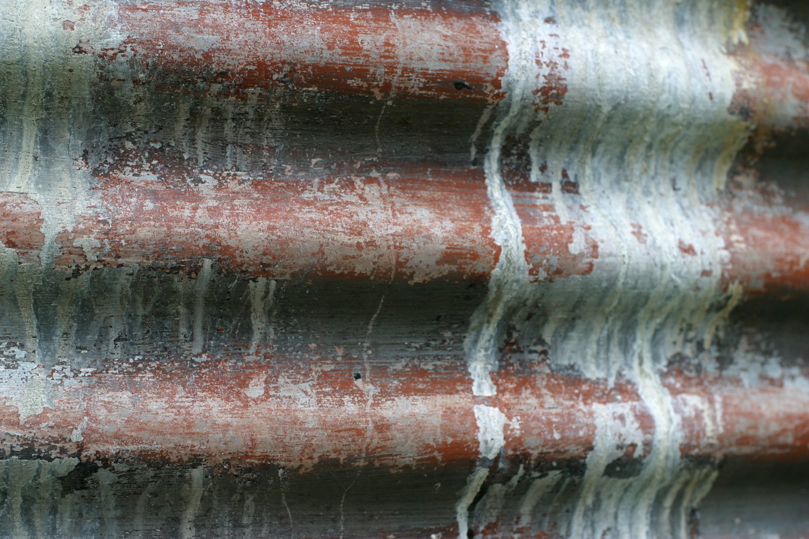 several rusty pipes are all covered in brown and white