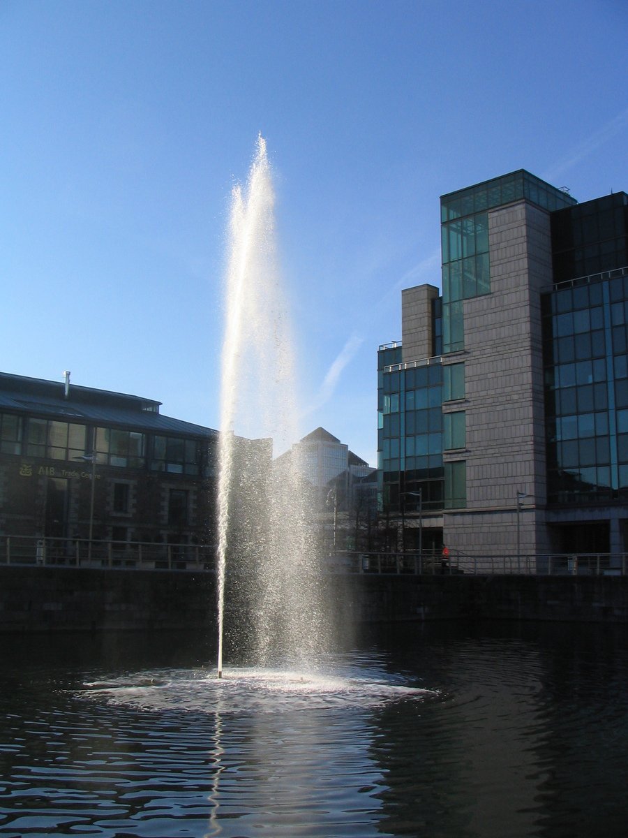 a big fountain spewing water in the air near a building