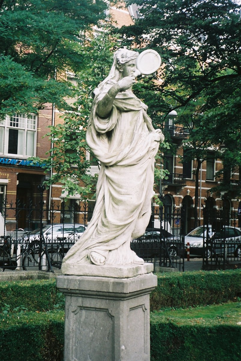 a statue in a park with a building in the background
