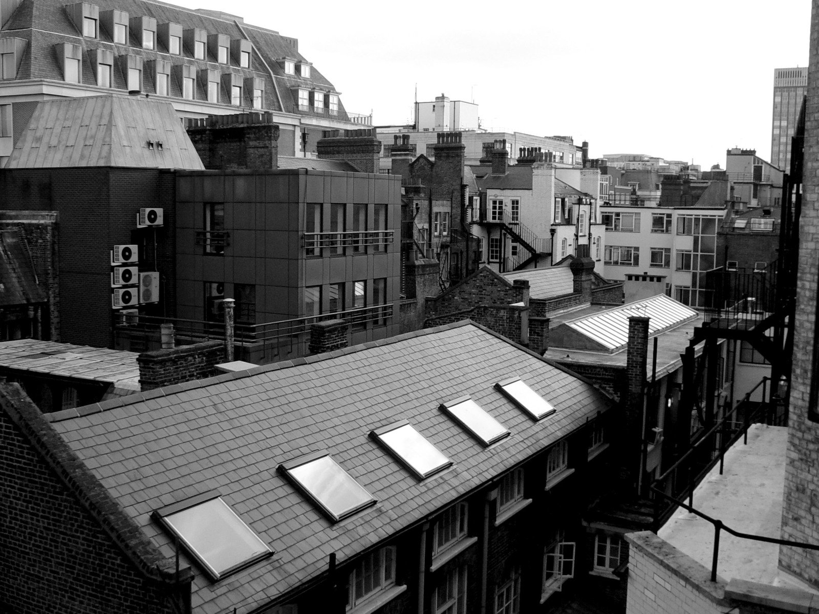 a black and white image shows a very high angle view of the roofs of the buildings