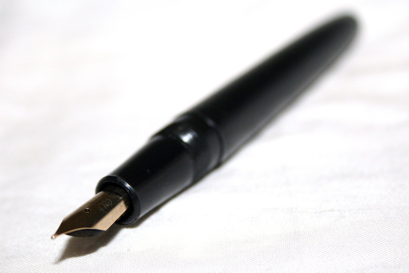 a pen sitting on a white background with black ink