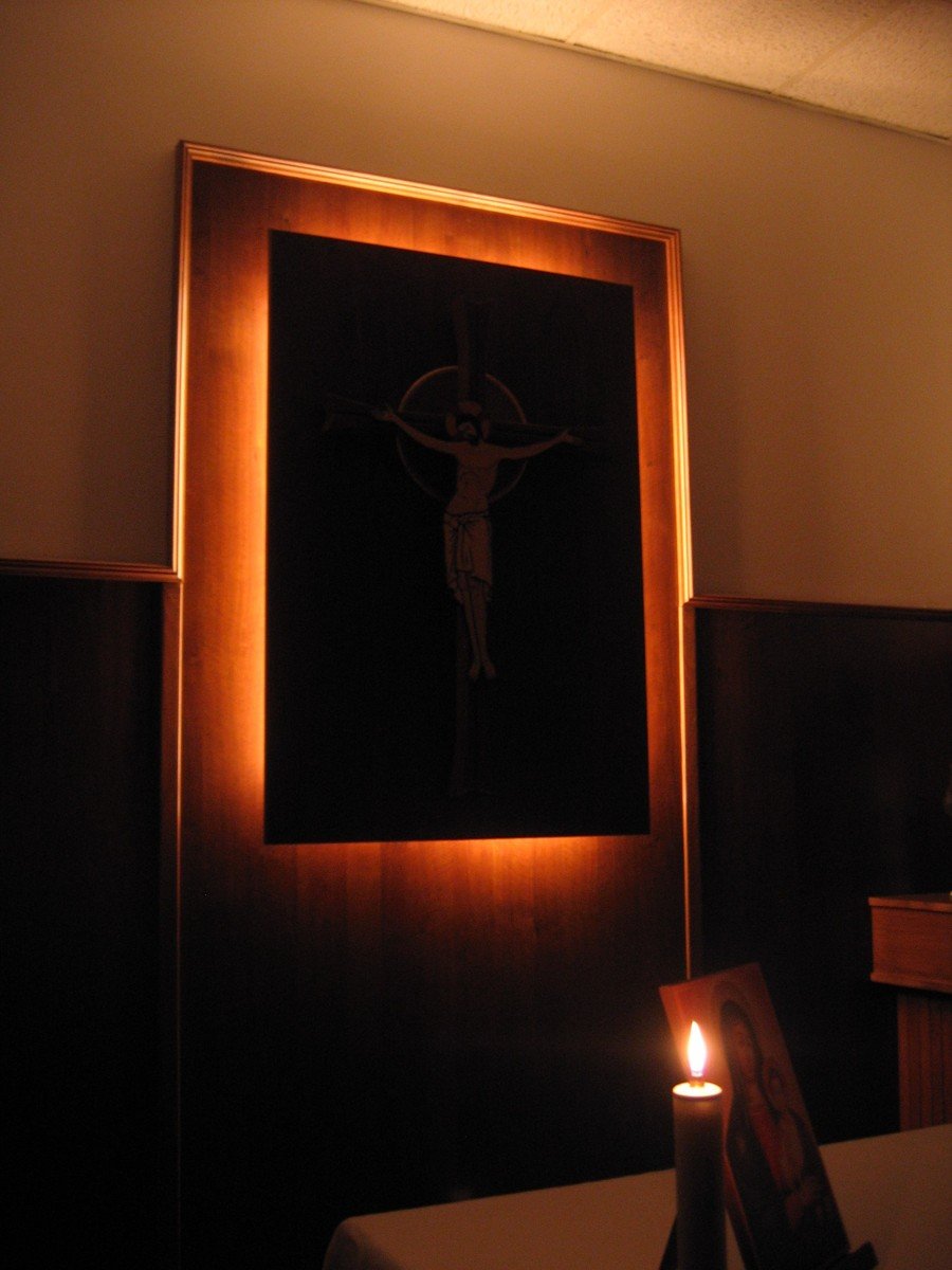 a lighted candle is lit next to an image of the christ on display