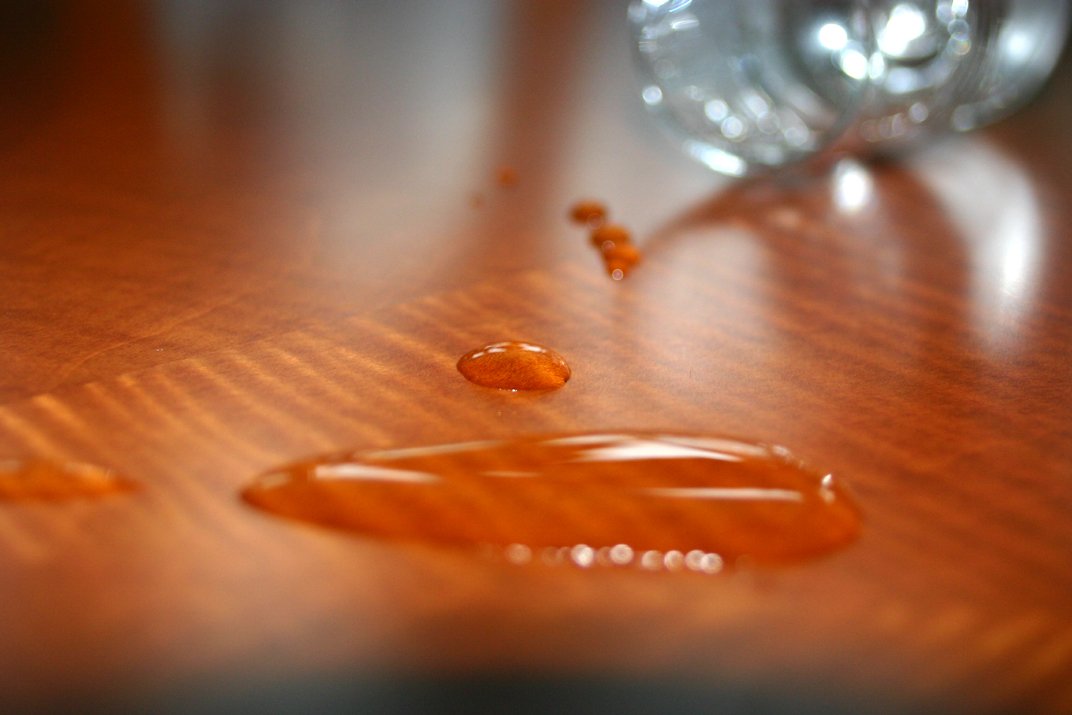 several brown drops of liquid sitting on a wooden surface