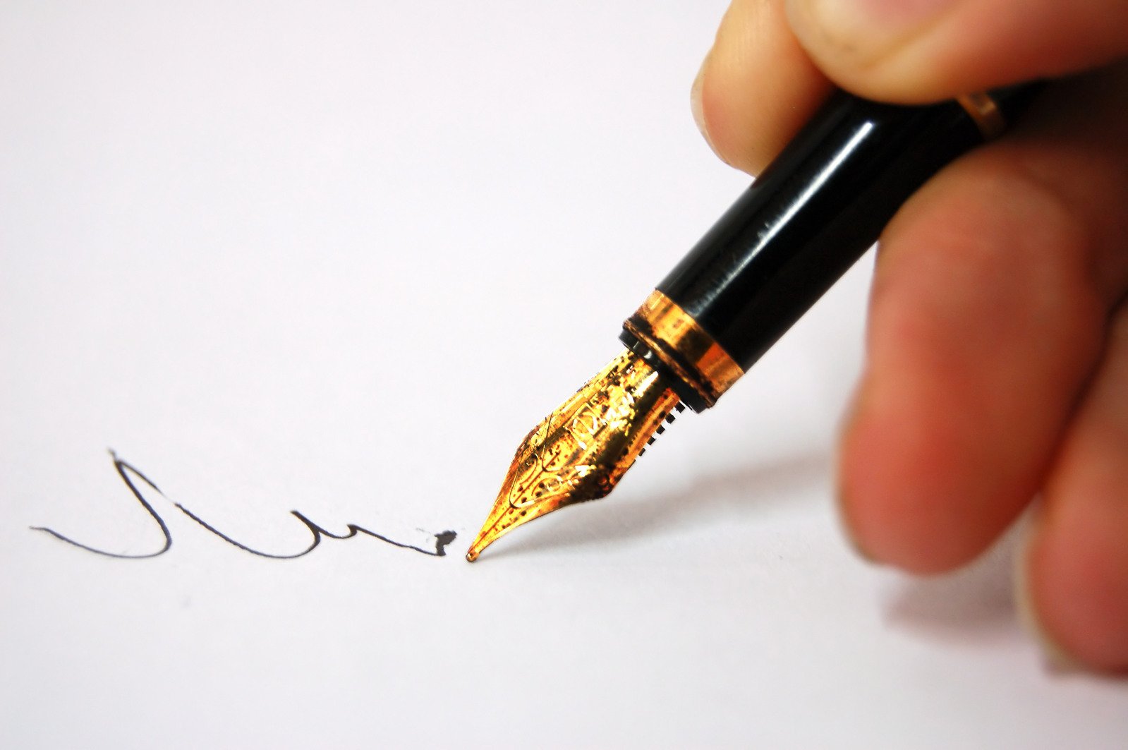 a person with a pen in their hand writes soing on paper