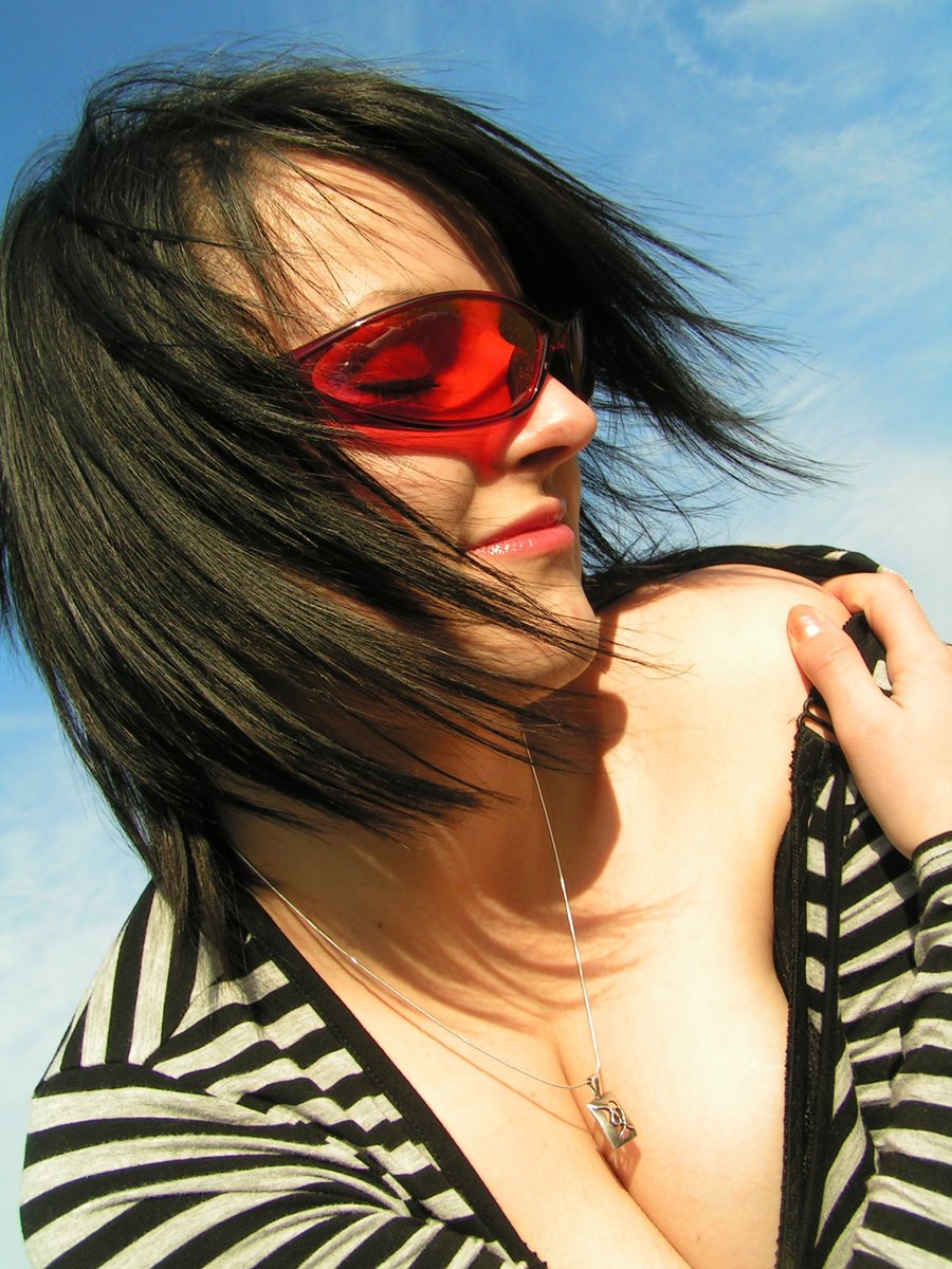 young woman with dark hair and red glasses posing for po