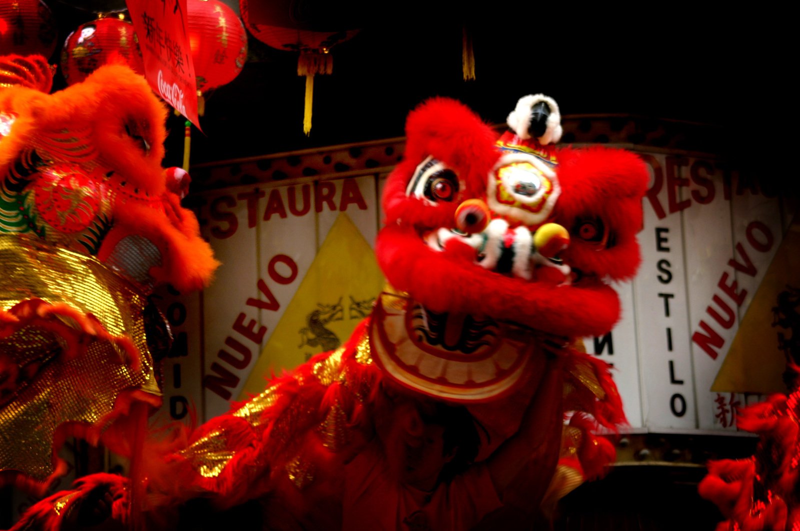 a fireworked lion dance costume stands beside other elaborate chinese decorations