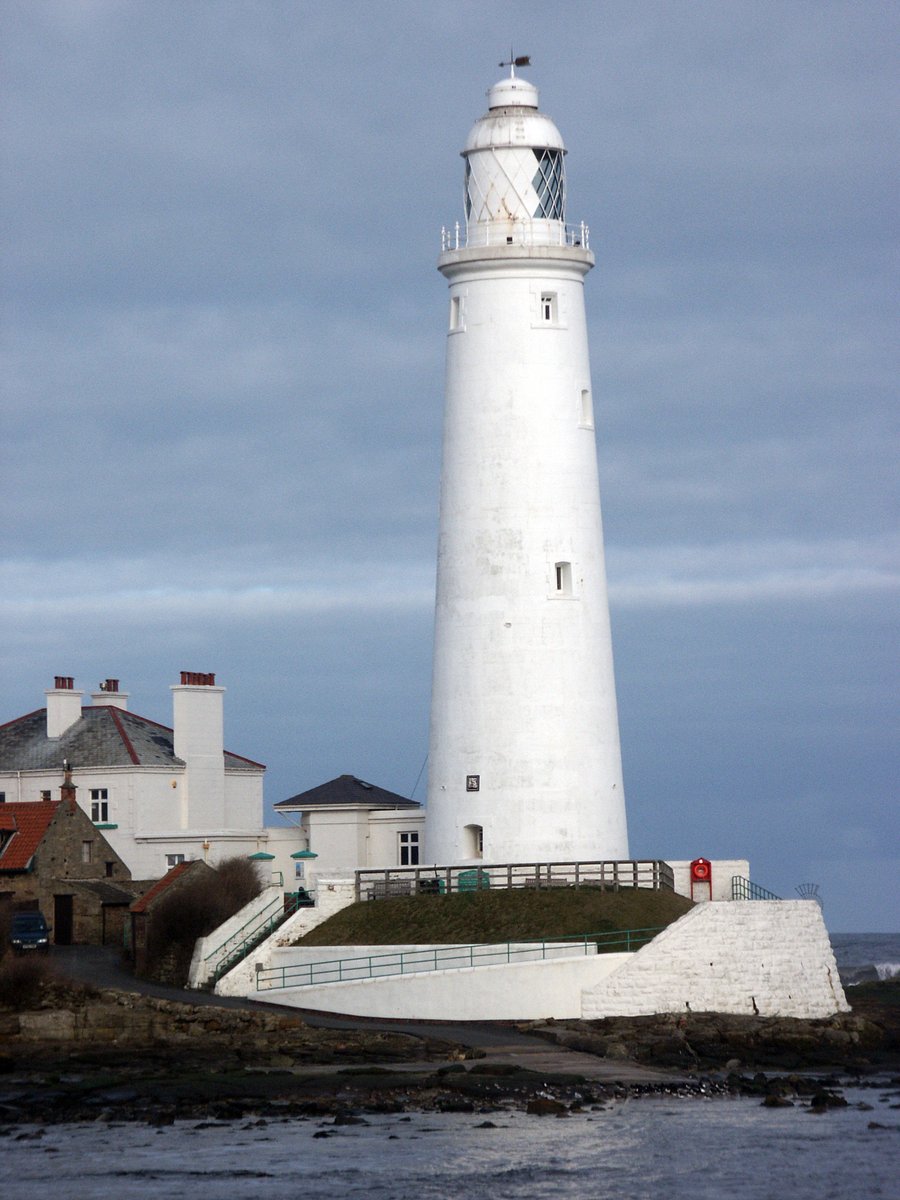 the lighthouse is by the sea with buildings around it