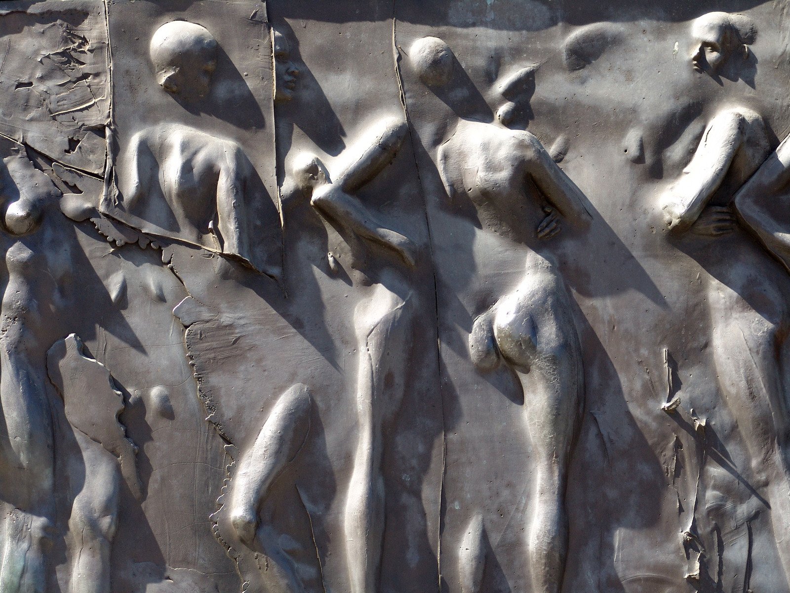 four stone statues of human bodies are placed next to each other