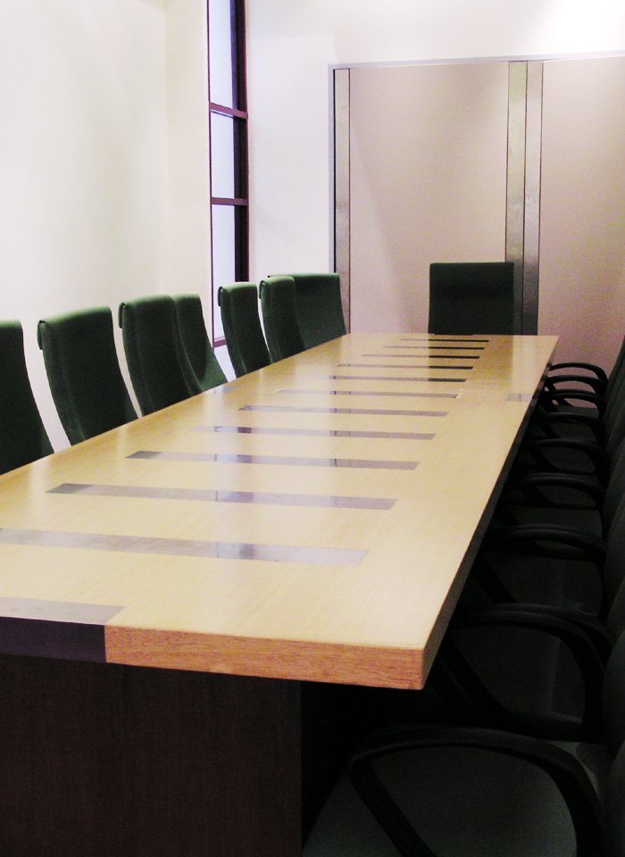 a large wooden conference table next to many black chairs
