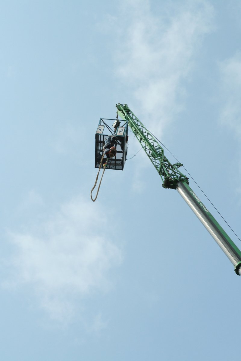 a man with a bucket on a tall crane