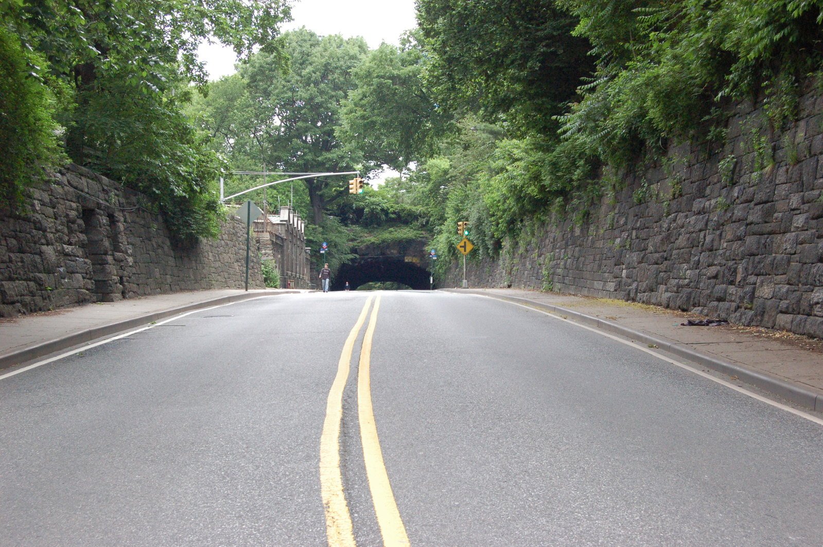 a street with a rock wall and two yellow lines