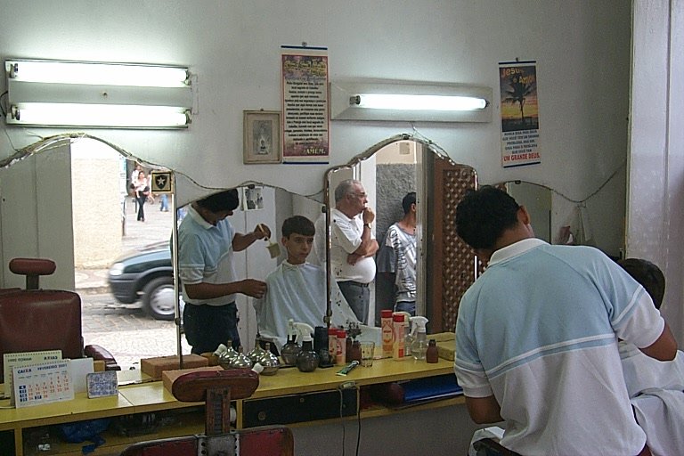 a man in a blue shirt is getting his hair cut