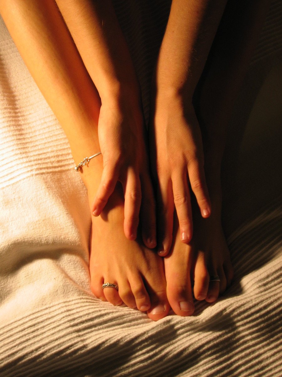close up po of person's hands and foot on white sheet