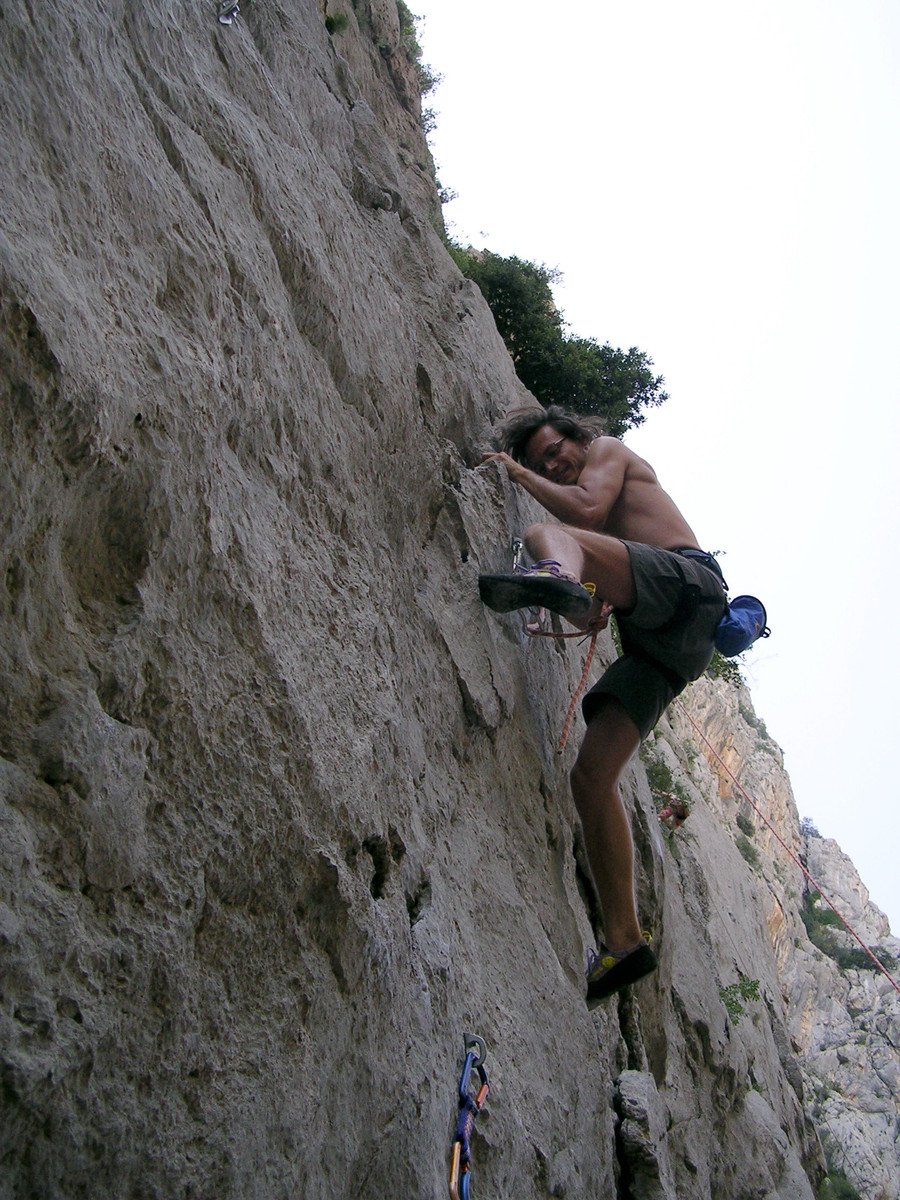 a man in shorts climbing up a very steep rock