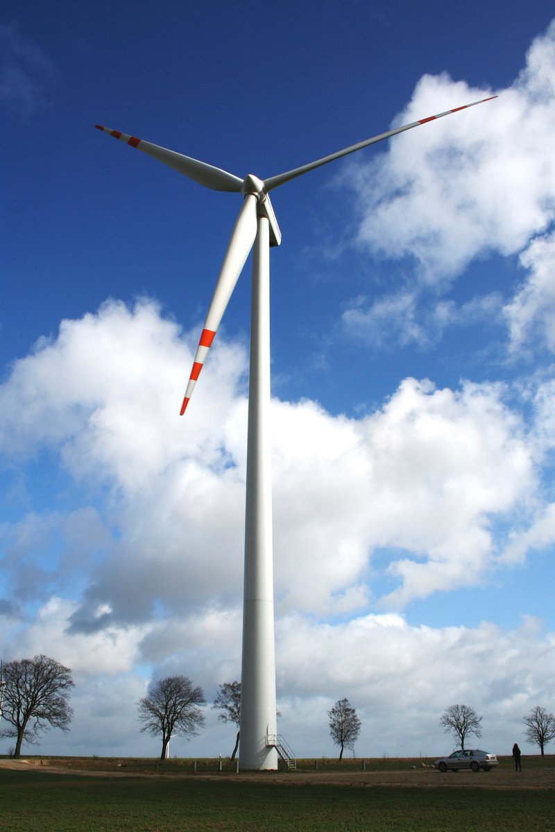 a wind turbine and trees on a sunny day